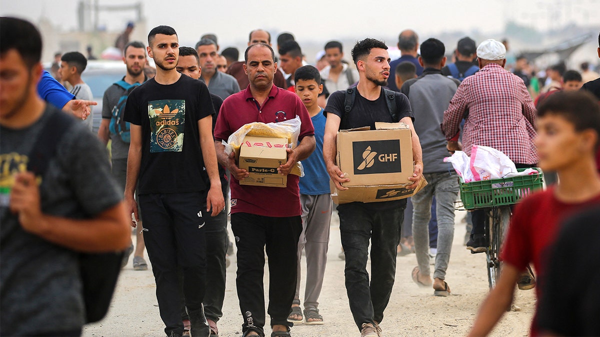 People carry boxes of relief supplies from the Gaza Humanitarian Foundation (GHF), a private US-backed aid group that has bypassed the longstanding UN-led system in the territory, as displaced Palestinians return from an aid distribution center in the central Gaza Strip on June 8, 2025.(EYAD BABA/AFP via Getty Images)