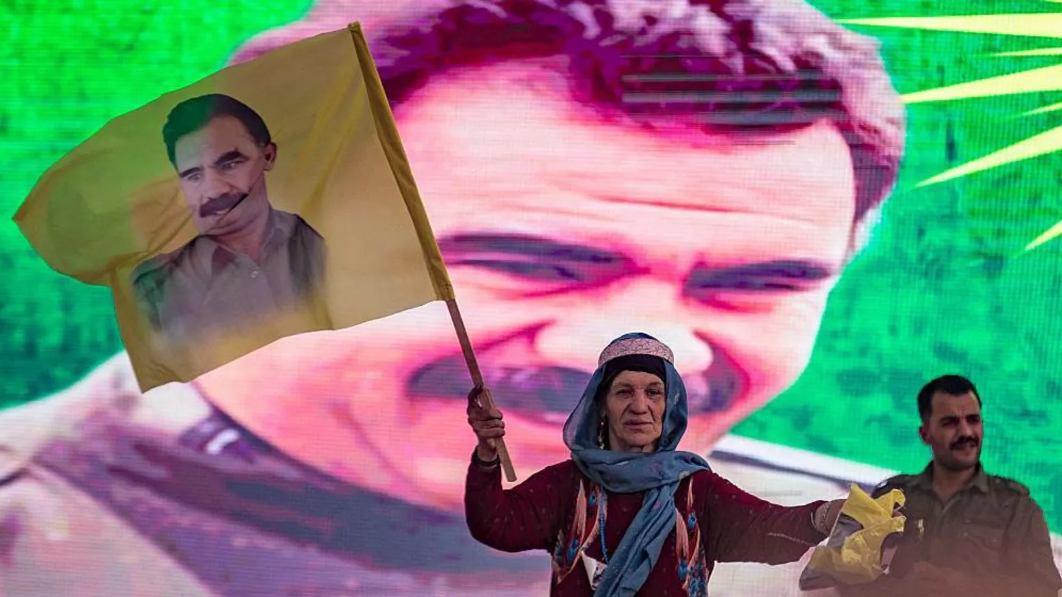 DELIL SOULEIMAN/AFP A supporter holds a flag with the face of Abdullah Ocalan, with his face also on the backdrop behind her