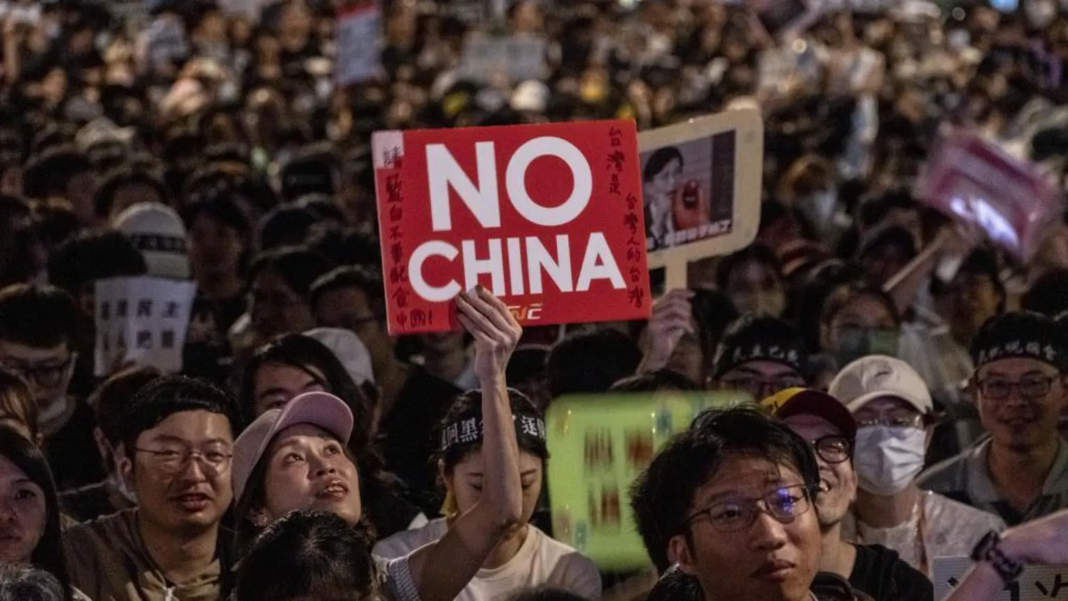 Getty Images At a night-time rally, a woman in a pink cap holds up a red and white sign that says in English